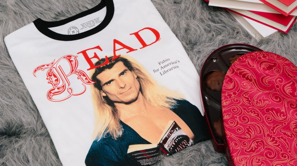t-shirt featurung the Fabio vintage READ poster. Nearby, a box of heart-shaped candy, candles , and a stack of books.