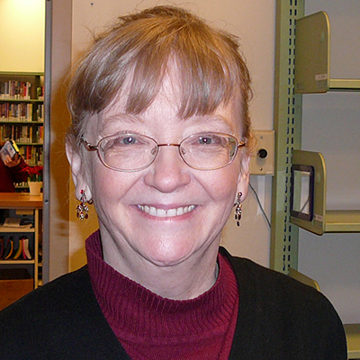 Photo of a woman with glasses smiling in a library
