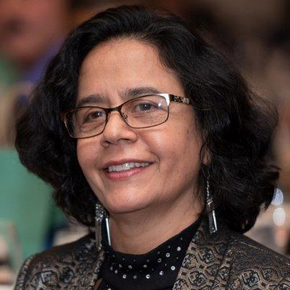 Photo of woman with dark hair and glasses looking away from the camera