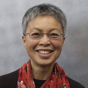 Photo of woman with short gray hair and glasses wearing a scarf and smiling