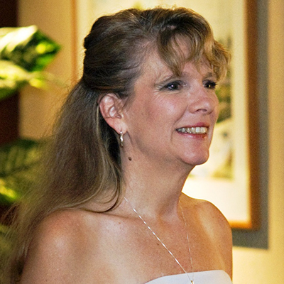 Photo of woman in a white dress smiling away from the camera