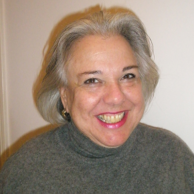 Photo of woman with gray hair wearing a gray sweater and smiling