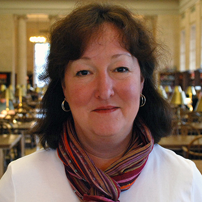 Photo of woman with dark hair wearing a white shirt and colorful scarf