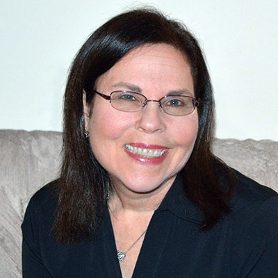Photo of a woman with straight black hair and glasses smiling