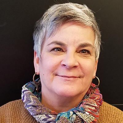 Photo of a woman with short gray hair and a colofrul scarf