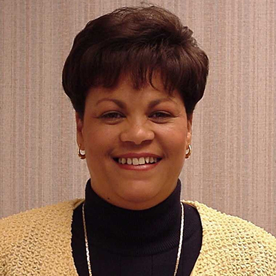 Photo of a woman with short dark hair wearing a yellow sweater and smiling