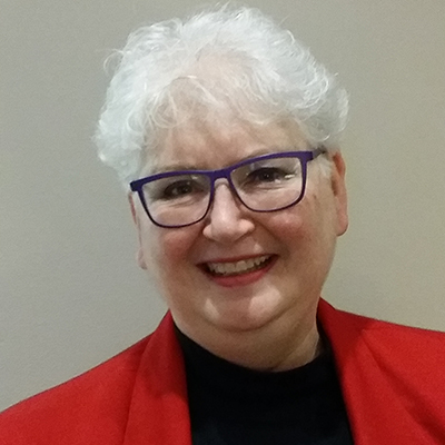 Photo of woman with short gray hair and glasses wearing a red blazer and smiling