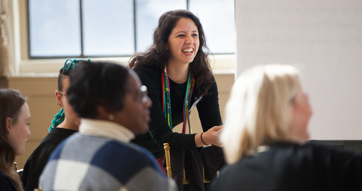 Image of a woman leading a discussion and smiling.