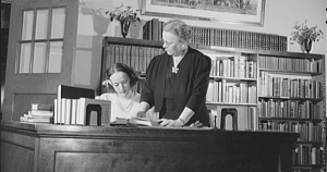 Archival photo of a librarian and assistant behind a desk