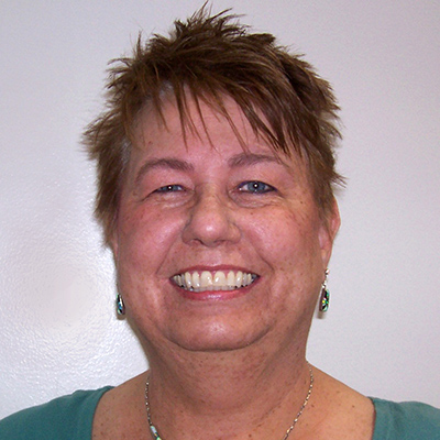 Photo of a woman with short hair and a green shirt smiling