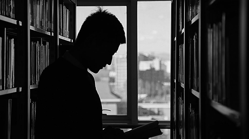Silhouette of man reading in a library