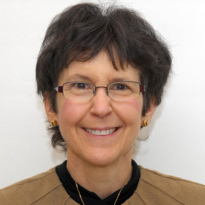 Photo of a woman with dark hair and glasses smiling