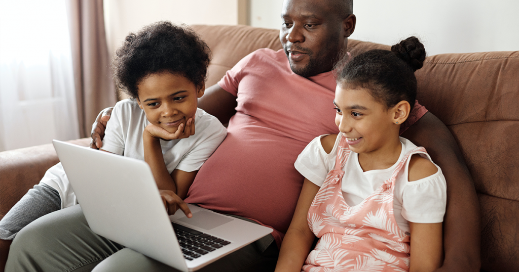 A family smiling and looking at a laptop