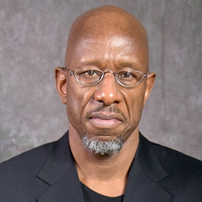 Photo of a bald man with a gray goatee wearing a black shirt