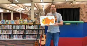 A librarian holds a picture book open to an illustration of a fish