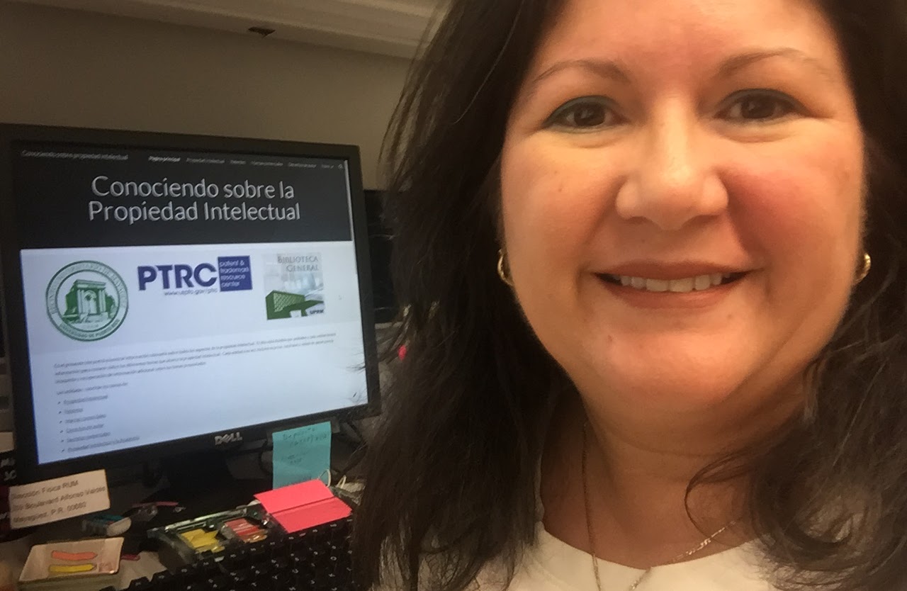 Photo of Gladys López-Soto in front of a computer displaying the website "Conociendo sobre la Propiedad Intelectual"