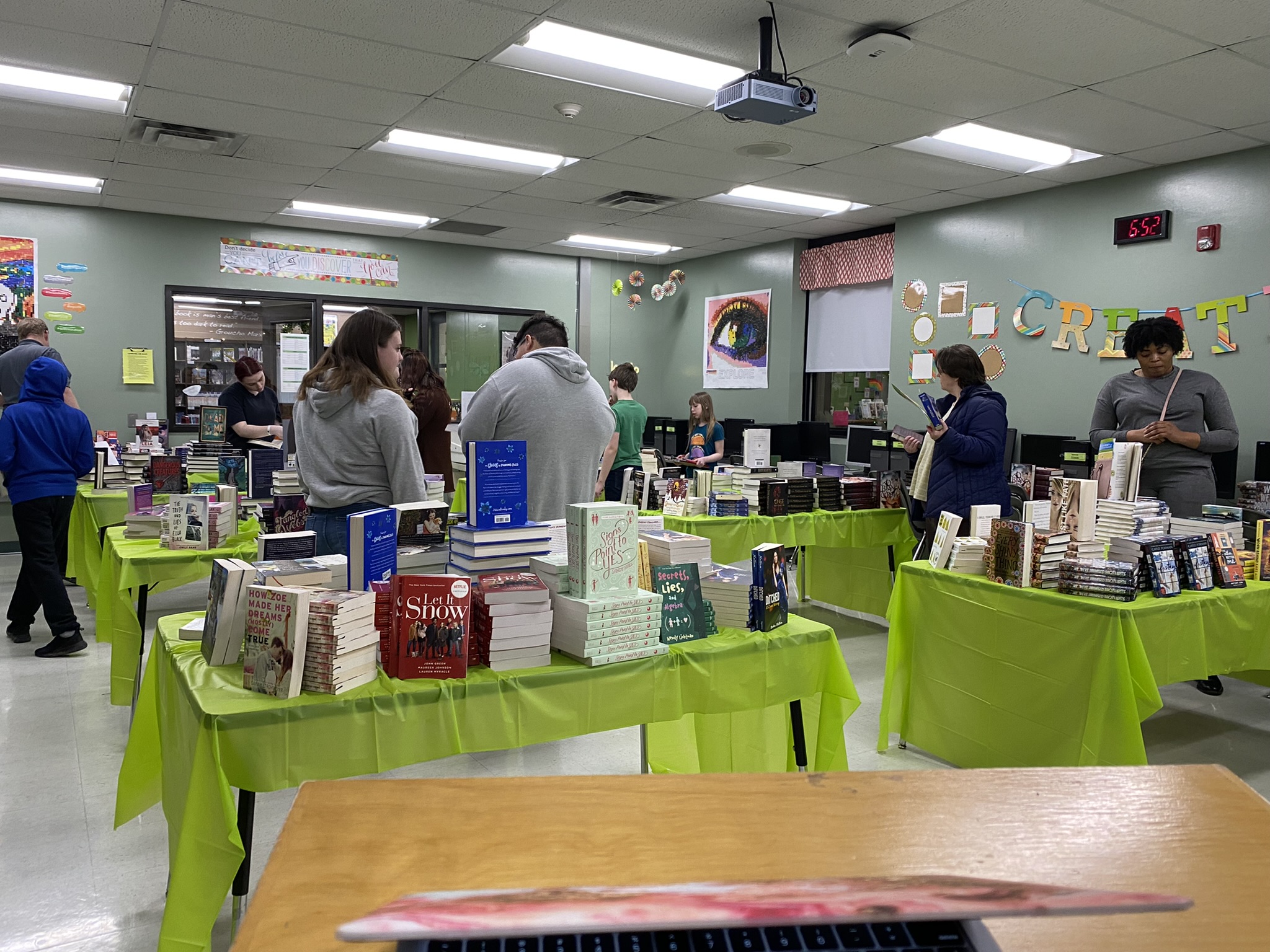 Photo of several students browsing tables with stacks of new books.