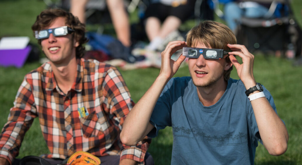 People are seen as they watch a total solar eclipse through protective glasses in Madras, Oregon on Monday, Aug. 21, 2017.