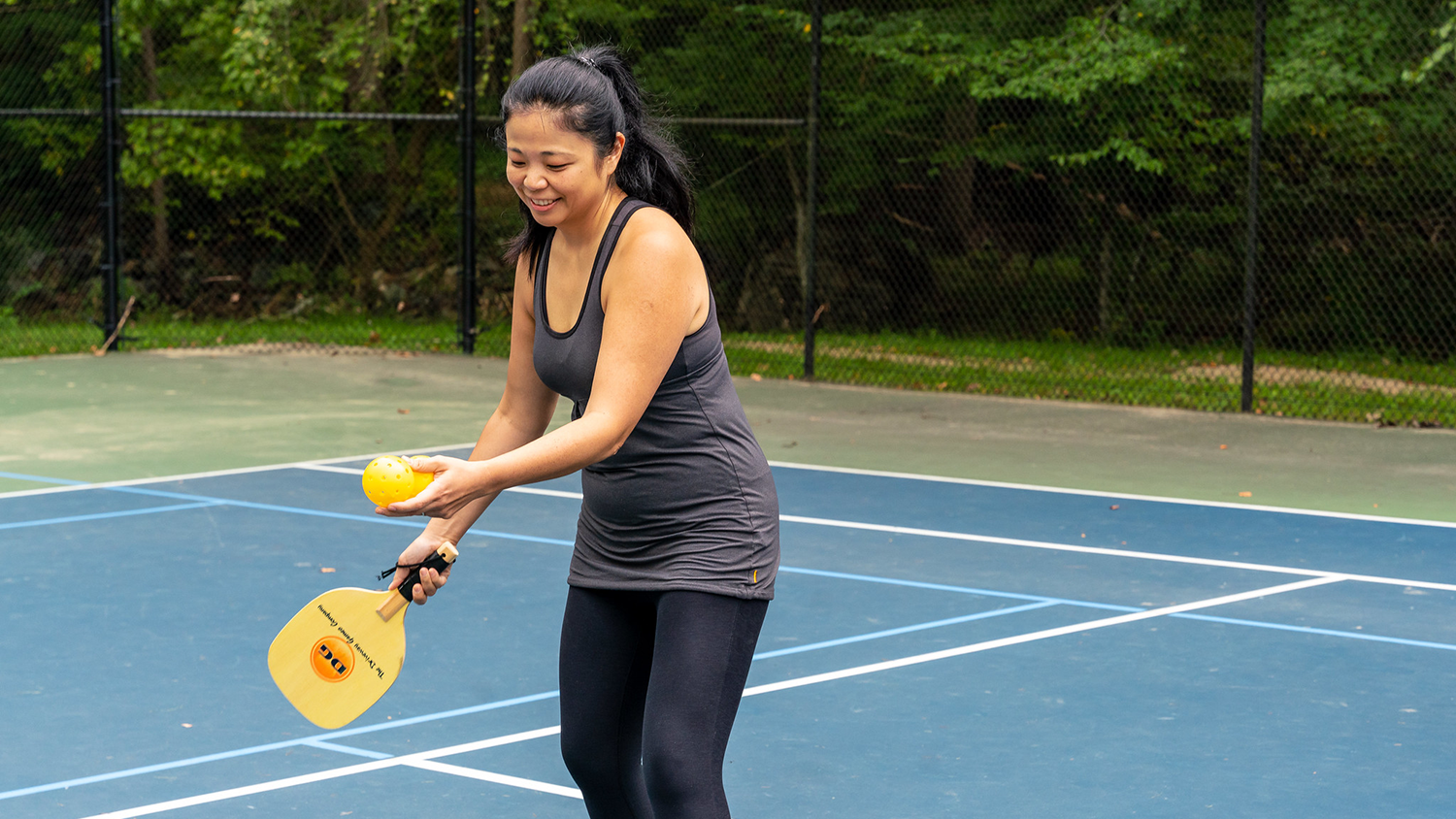 Woman about to serve on pickle ball court.