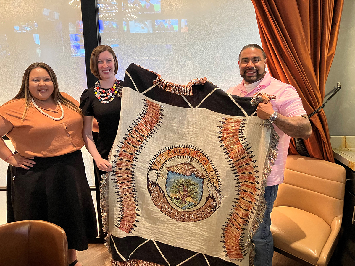 Photo of three people holding up a display of the Great Seal of the Wilton Rancheria Tribe