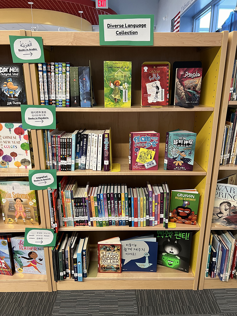 A bookshelf featuring a collection of books in multiple languages. A label at the top says "Diverse Language Collection" while labels on the side note books in Arabic, Mandarin, Spanish, and several others.