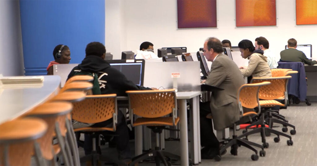 A diverse group of people using computers at a library.