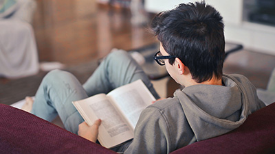 Teen boy reading on couch