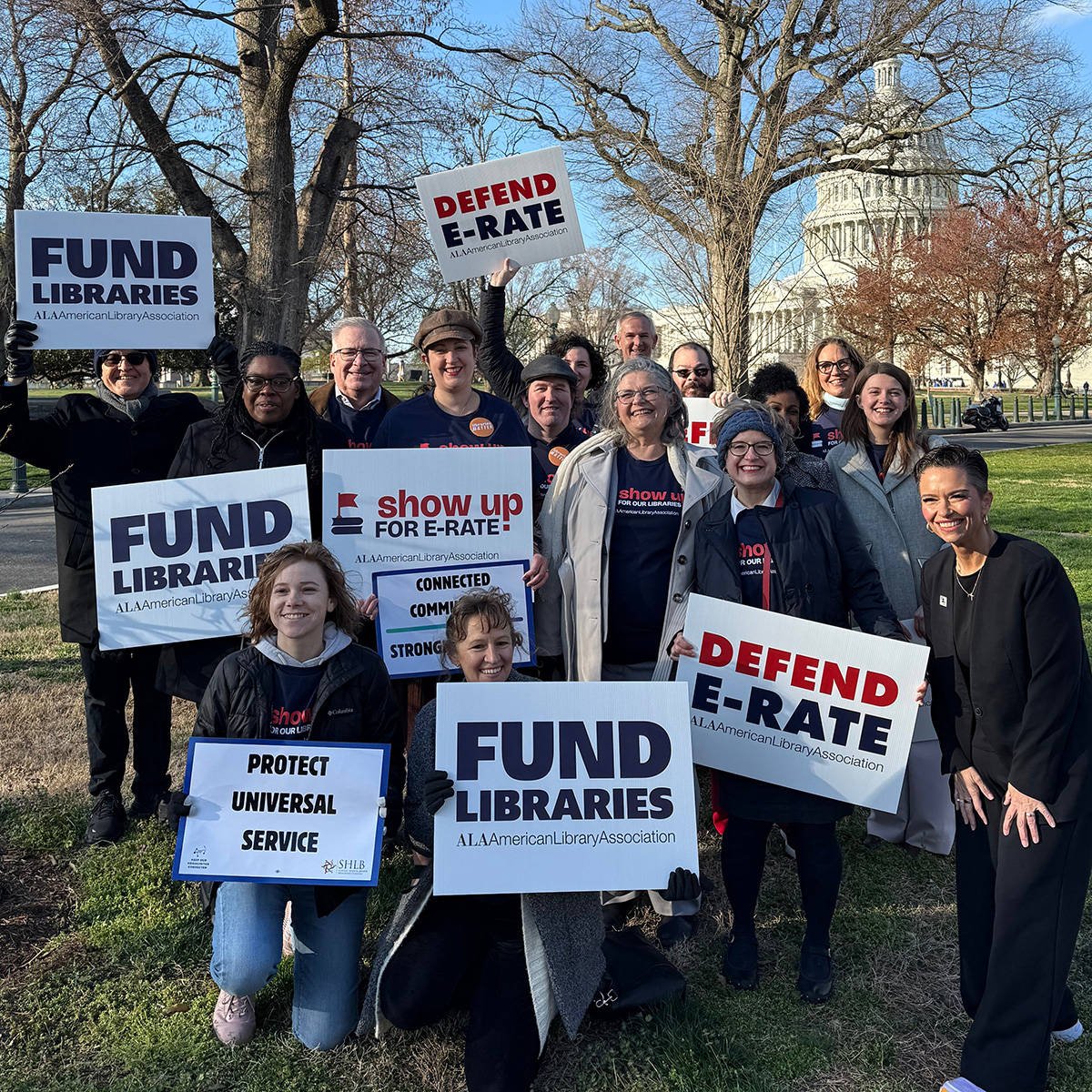A group of advocates in front of the U.S. Capitol holding signs that read "FUND LIBRARIES," "SHOW UP FOR E-RATE" and "DEFEND E-RATE"