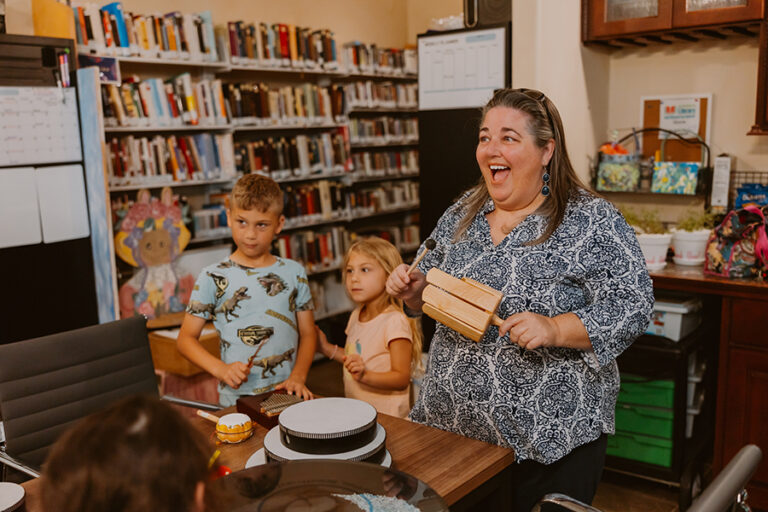 A library worker playing musical instruments with a group of kids