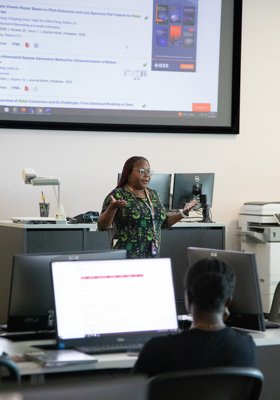 Photo of Mahasin Ameen teaching a class in front of a large projector screen