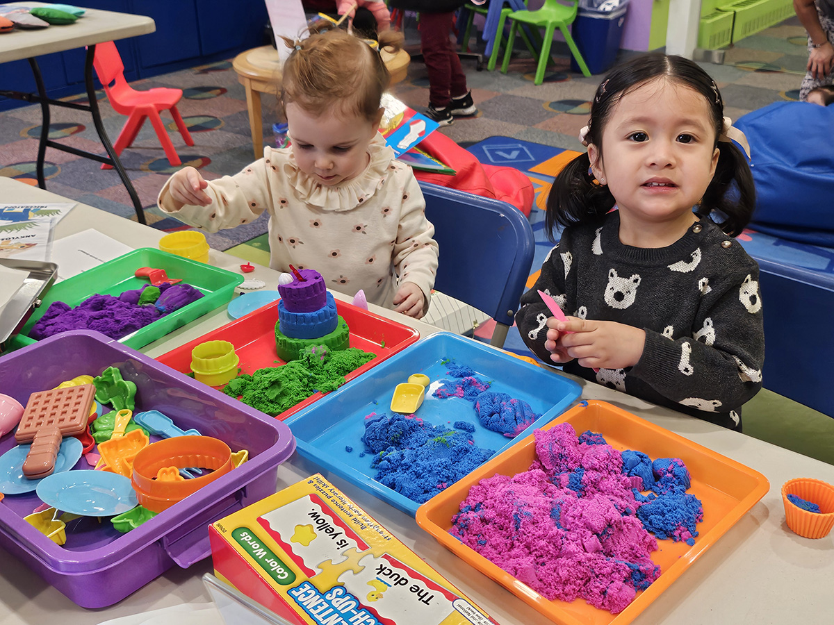 Two young children playing with colorful kinetic sand