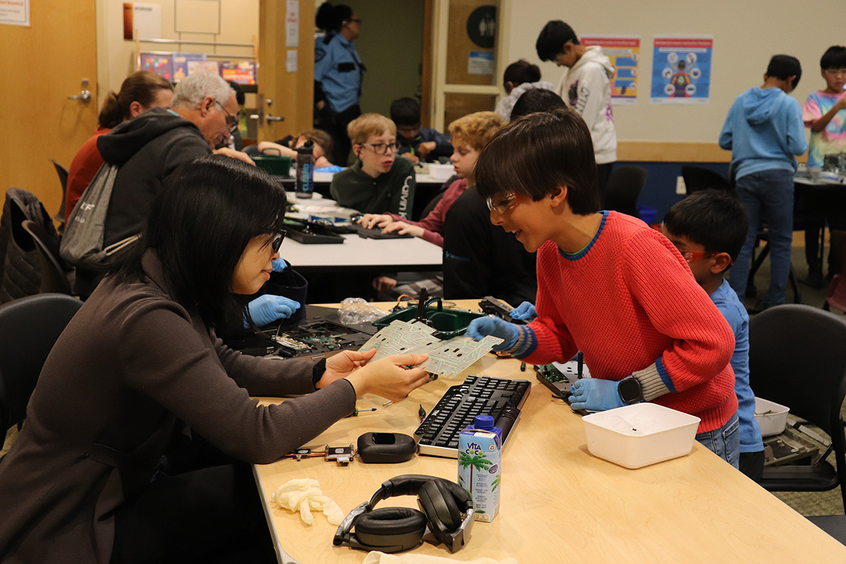 Two kids taking apart tech hardware at a library