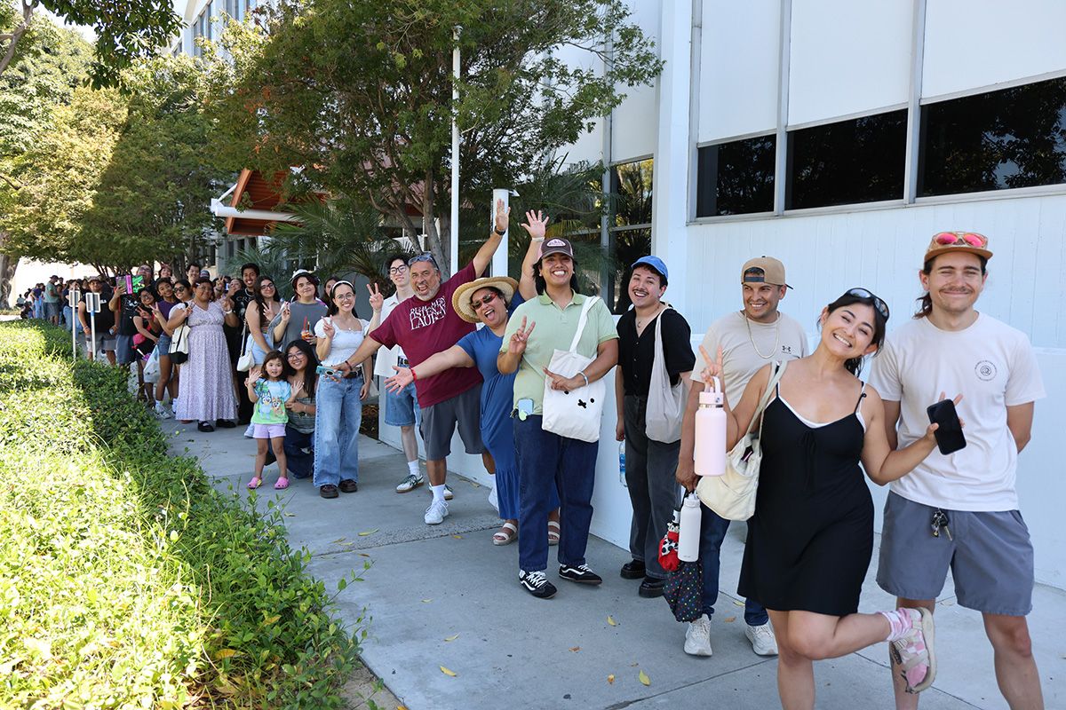 Photo of many happy people standing in a line outside of a library